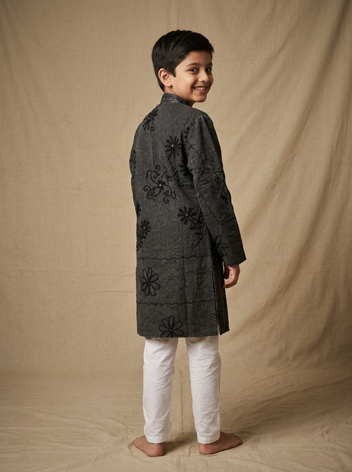 Boy wearing charcoal black machine embroidered floral vine cotton indo western kurta with off-white pajama back view