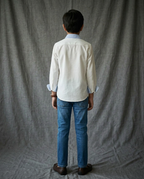 Boy wearing white cotton shirt with contrast light blue striped collar and cuffs back view